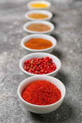 Bowls with aromatic spices on grey background, closeup