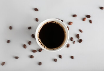 Takeaway paper cup of coffee and beans on light background