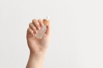 Naklejka premium Female hand with bottle of serum on white background, closeup