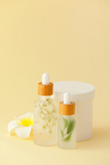 Fototapeta na wymiar Bottles of natural serum with flower on yellow background