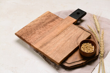 Fototapeta premium Wooden cutting boards and bowl of wheat grains on light background