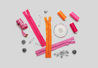 Set of colorful zippers and sewing supplies on light background