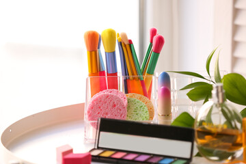 Obraz na płótnie Canvas Organizer with colorful makeup brushes and sponges on table near window, closeup