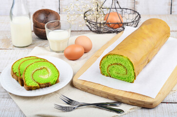 Pandan roll cake or chiffon cake, is Asian take on Western sponge cake in white plate served on wooden