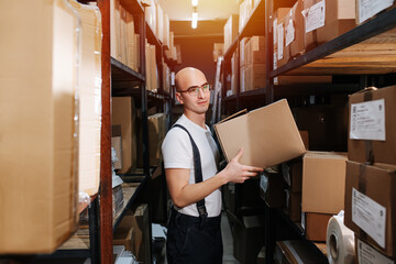 Thougtful male warehouse worker holding a box, spacing out