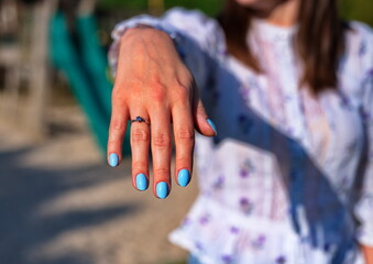 Closeup of woman's hand posing with blue nails and engagement ring