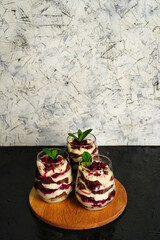 Sweet dessert with brown chocolate and white cream in a transparent glass. The cake is decorated with a mint leaf, birthday portioned cake.
