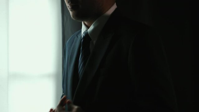 Confident businessman adjust classic blue suit with necktie finished dressing and walked out of the room. Handsome man wearing a nice suit on wedding day.