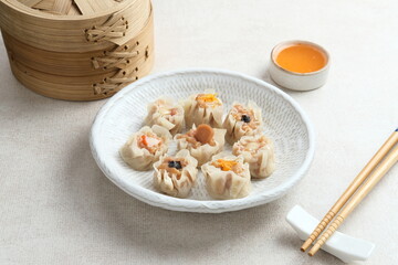 Dimsum (Mini Dimsum) with various toppings, served in a white plate with spicy sauce. 
