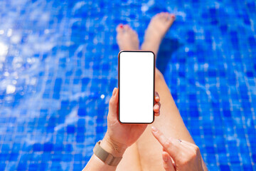 Woman holding mobile phone with empty white screen while sitting by the pool