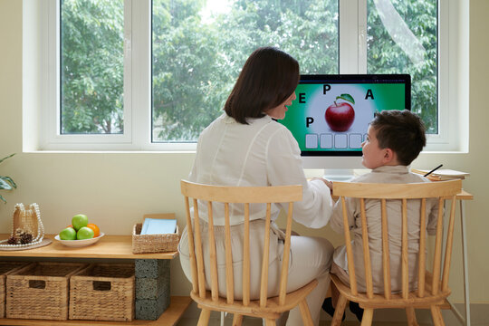 Home Tutor Teaching Boy English Language While They Are Sitting At Computer Desk