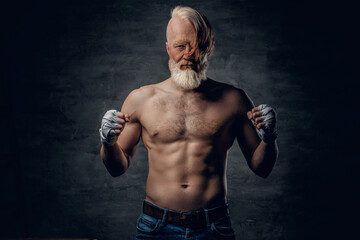 Photo of topless senior boxer with stylish hairstyle and muscular build against dark background.