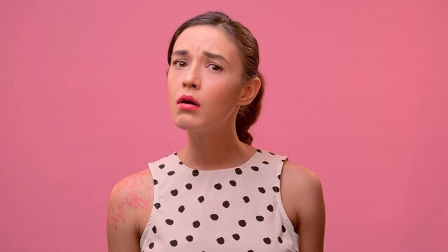 Young pretty distressed Caucasian woman gets upset when hears bad news is sad and sighs heavily shaking head refuses to believe in what is happening stands on pink studio background