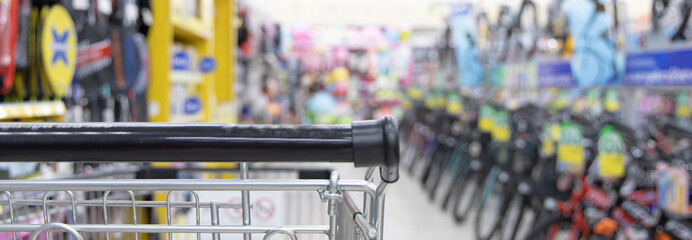 Shopping cart in supermarket, Abstract blurred photo in shopping malls, Cart in the market, wide variety of products are placed on the shelves for an orderly display.