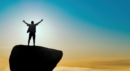 Man standing on cliff above bright sky with copy space