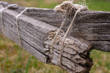 a broken wooden fence repaired with a cord