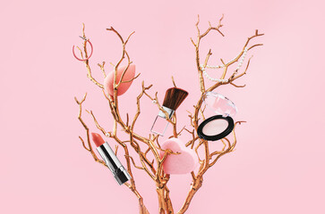 Tender pink feminine makeup tools and accessories. brushes blush lipstick sponges pearls on golden tree branches on candy pink. Birthday beauty cosmetics blogger advert bridal concept.