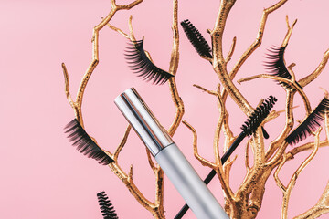 Tender pink feminine makeup tools and accessories.mascara with false lashes eyelash on golden branches on candy pink. Birthday beauty cosmetics blogger advert border concept.