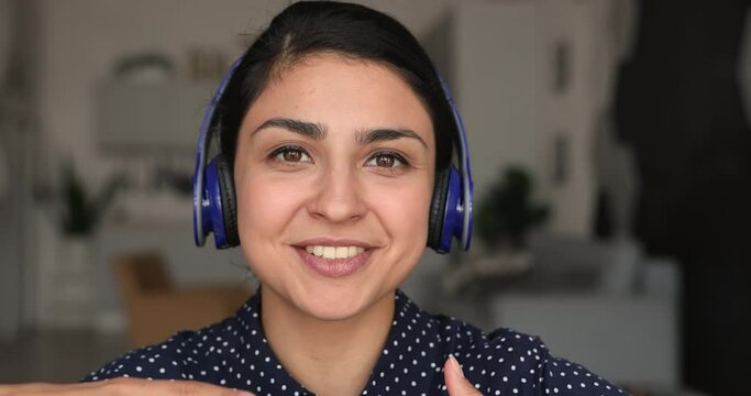 Close up Indian vlogger sit indoor wear headphones talk to camera, record new videovlog for internet subscriber, student talk to schoolmate use videocall app. Share knowledge, video call event concept