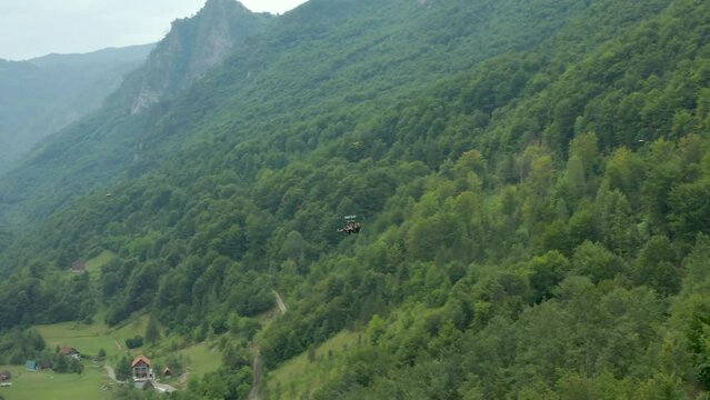 People slide along the zip line over the forest in Montenegro