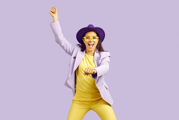 Funny woman dancing against lilac background. Studio shot of happy beautiful young girl in purple...