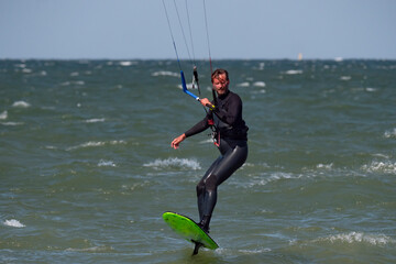 Male Kite Foil Surfer with beard and long hair on the sea. 