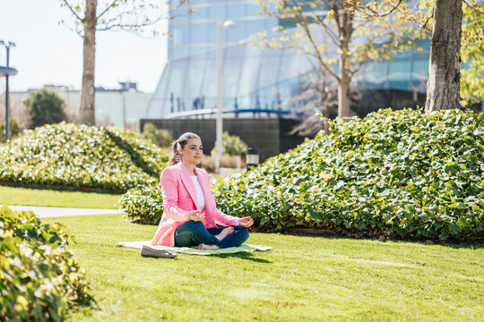 Businesswoman sitting cross-legged meditating in office park
