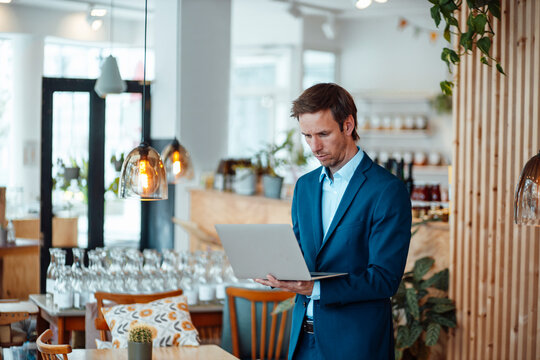 Freelancer using laptop standing in cafe