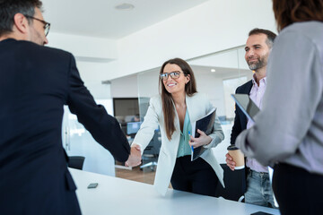 Businesswoman shaking hands with colleague in office