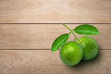 Fresh green lime with greren leaf isolated on wooden table background. Top view. Flat lay.