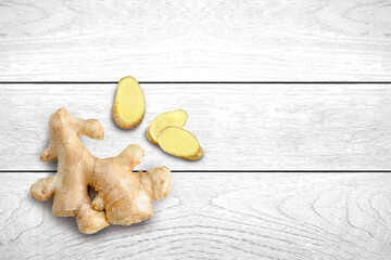 Ginger root with slices isolated on white wooden table background. Top view. Flat lay. Copy space.