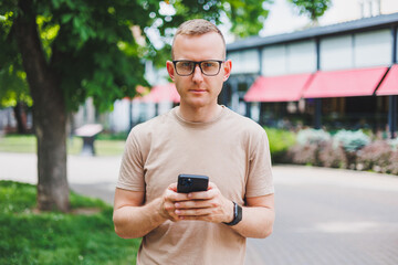 Portrait of handsome mature businessman holding messenger bag, wearing stylish eyeglasses looking...