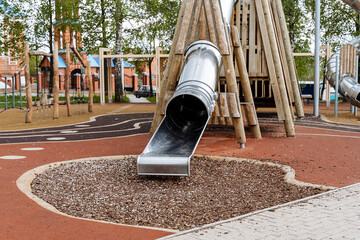 Modern children's playground for outdoor games, a slide pipe made of metal, pyramids made of wood,...