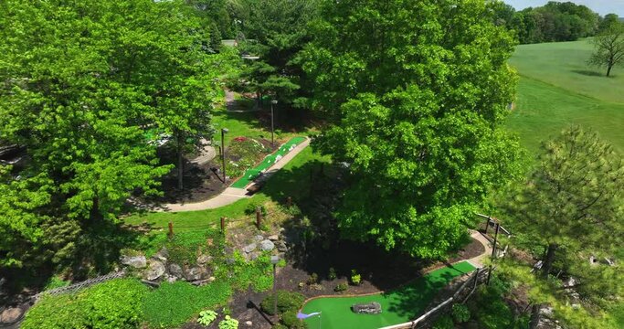 Aerial view of mini golf course on beautiful spring day. Trees reveal go karts racing on small track. American leisure activities.