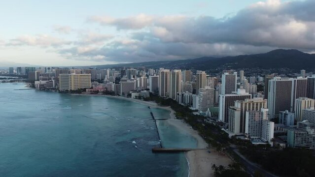4K cinematic clockwise shot of Waikiki from the East end during sunrise in Oahu. This stunning Hawaiian coastline was filmed using a DJI Mini 2 drone.