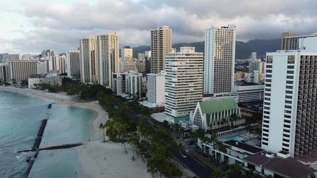 4K cinematic drone shot of Waikiki Beach and the hotels that line it during sunrise on a cloudy day in Oahu. This colorful Hawaiian cityscape was filmed using a DJI Mini 2 drone.