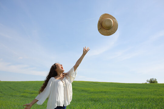 Happy woman throwing pamela to the air in a field