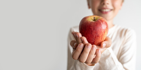Smiling child boy giving red apple over white background. Delicious and healthy food, proper nutrition. Banner extra wide. Copy space © Chiralli