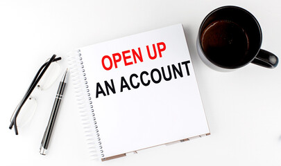 Coffee,glasses,pen and notebook written with OPEN UP AN ACCOUNT on white background.