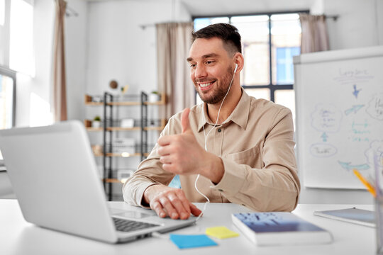 distance education, school and remote job concept - happy smiling male teacher with laptop computer having online class at home office showing thumbs up