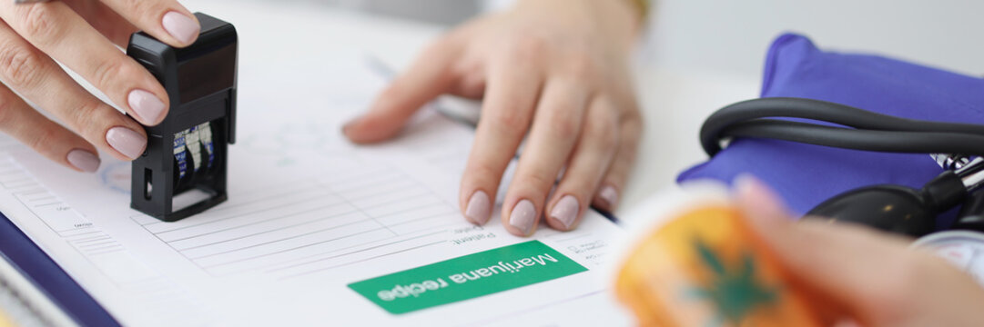 Close-up of practitioner hand giving stample on prescription
