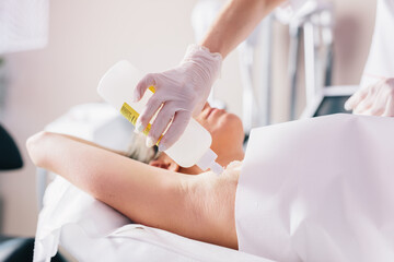 Woman on laser hair removal treatment on underarm, applying gel