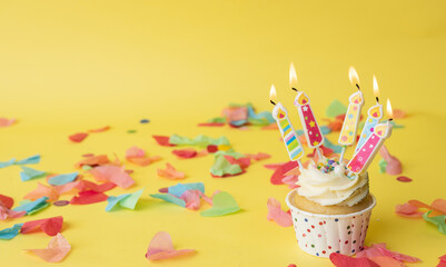 A colorful birthday cupcake with a colored candle
