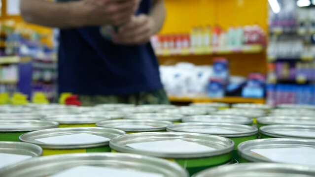 Close-up of many cleaning powder tins on a store counter and a male buyer takes one