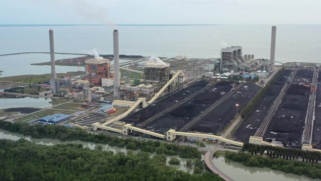 Coastal coalfield and industrial ultra-supercritical coal-fired power plant with smokes raising from chimney located at lekir bulk terminal jalan, teluk rubiah, manjung, perak, malaysia.
