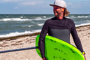 Portrait of a male kite foil surfer with a board on the beach