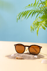 Fototapeta na wymiar Trendy sunglasses on a beach with palm leaves. Womens sunglasses on sand - summer fashion concept. Fashionable accessories. Optic store discount, sale, offer. Vertical, social media