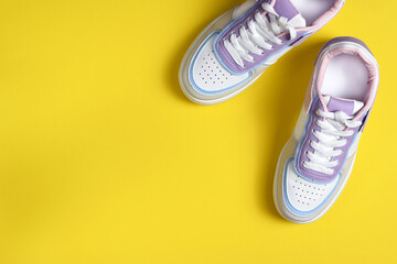 New colored sneakers with white laces on a yellow background. Fashion footwear. Top view, flat lay. - obrazy, fototapety, plakaty