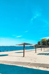 Straw beach umbrellas for shade near the river on the background of the landscape.