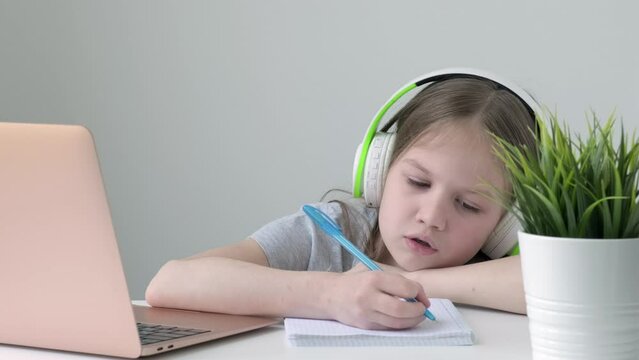 Caucasian homeschooling kid girl feeling bore to do homework and assigned job from remote school teacher. Child making boring face when working on computer at home. Children remote online education